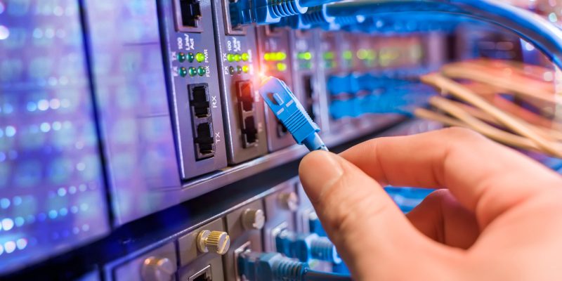 man working in network server room with fiber optic hub for digi man working in network server room with fiber optic hub for digital communications and internet